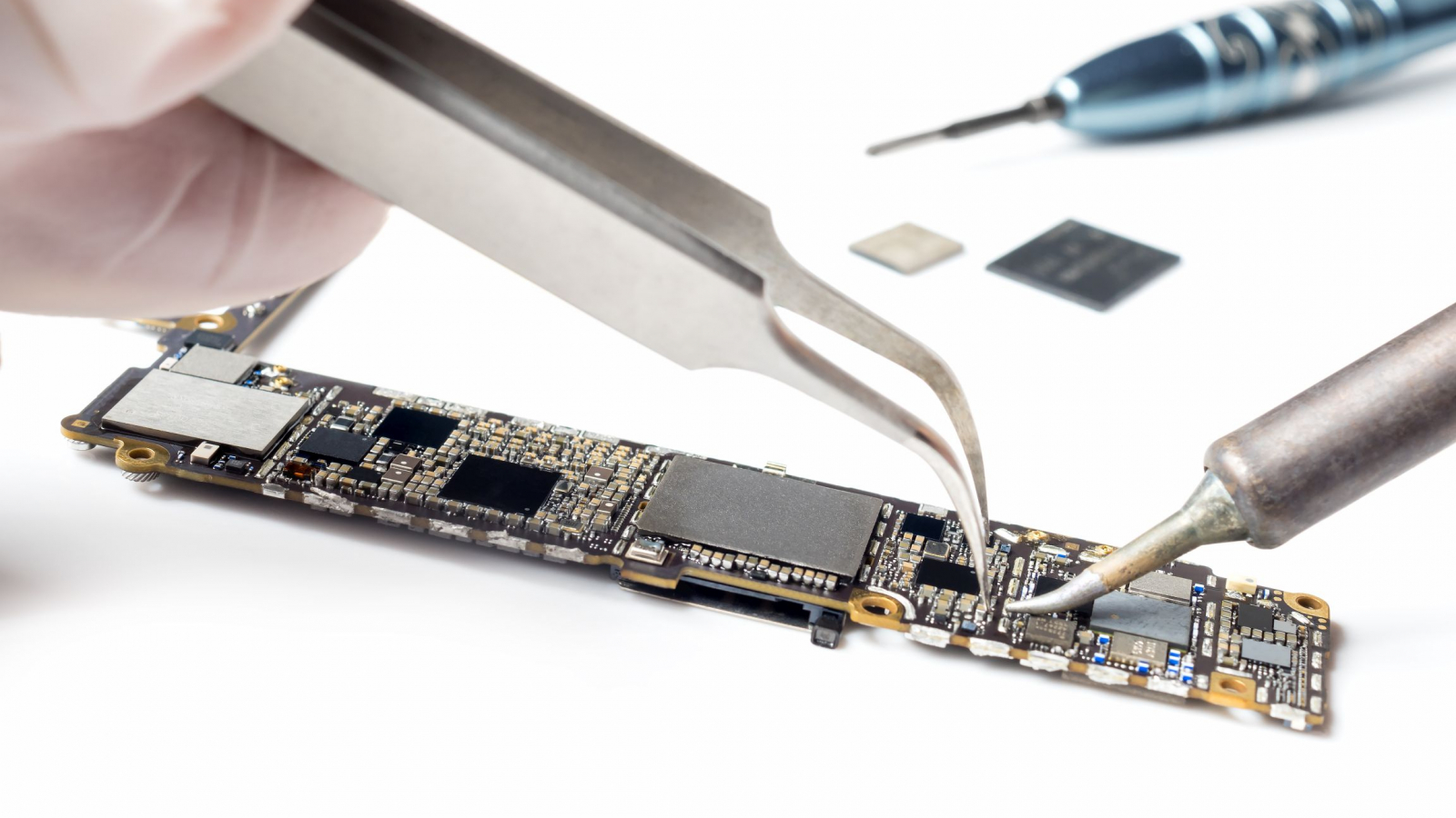 Close-up image of technician replacing microchip of smartphone logic board
