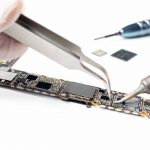Close-up image of technician replacing microchip of smartphone logic board